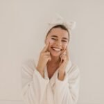 smiling-young-caucasian-woman-terry-bathrobe-squints-applies-transparent-patches-eyes-white-background-home-spa-facial-concept_197531-31559