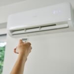 Adjusting,Air,Conditioner,Temperature,With,Remote,Control.,Hand,Holds,Remote